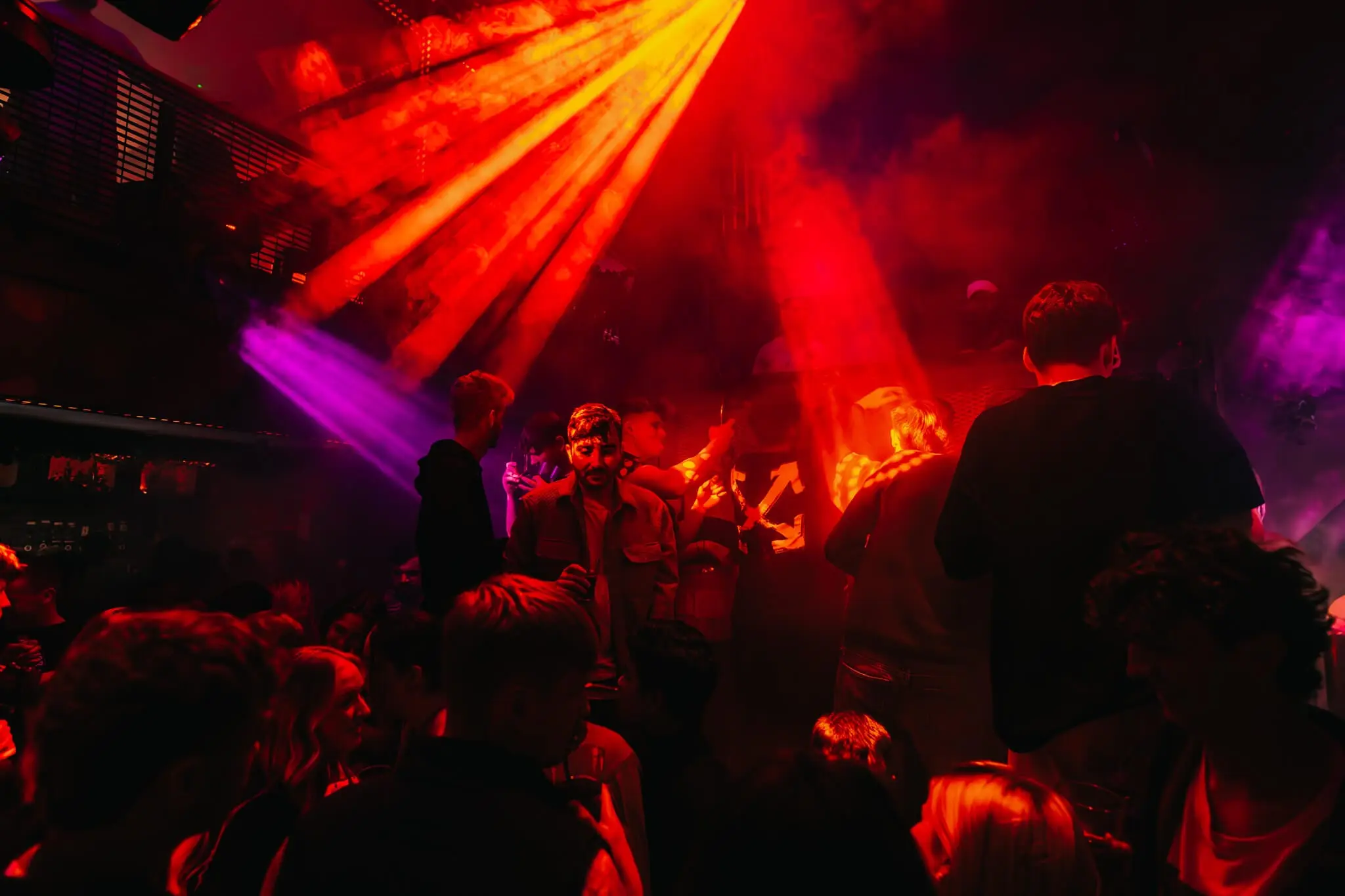 The main club floor at Thompsons under red lighting, packed to the DJ booth